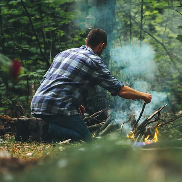 Camper lighting a campfire in the bush